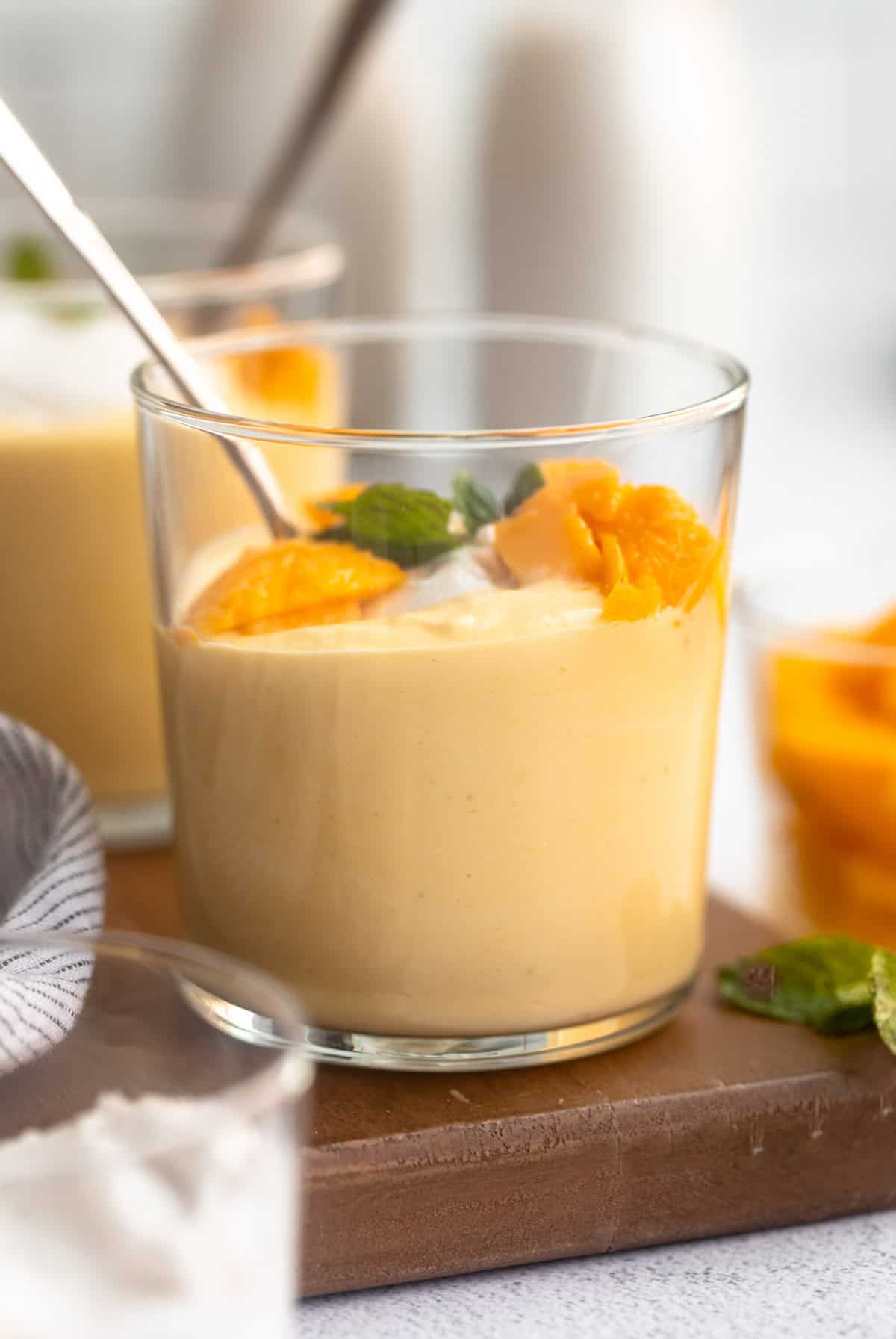 mango mousse in a glass jar with fresh mango on top