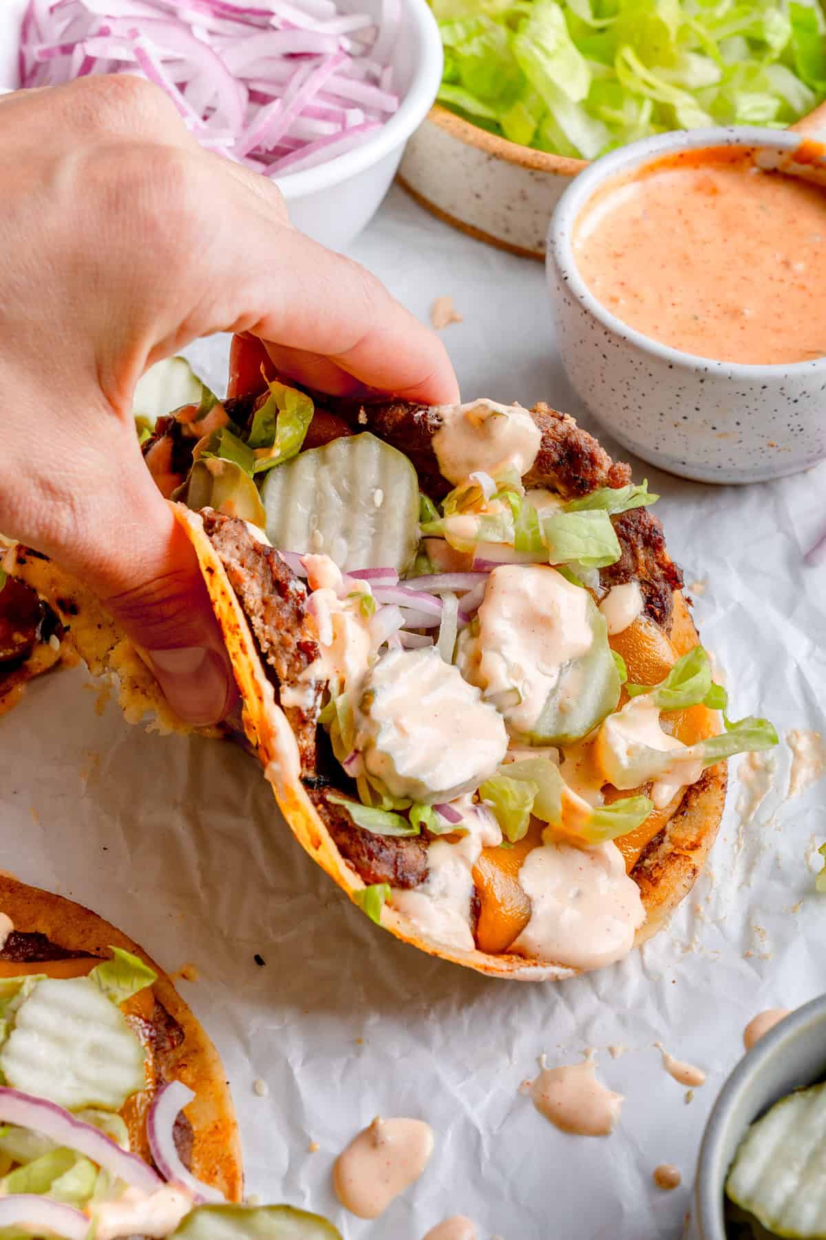 hang picking up the smashburger taco with sauce on top