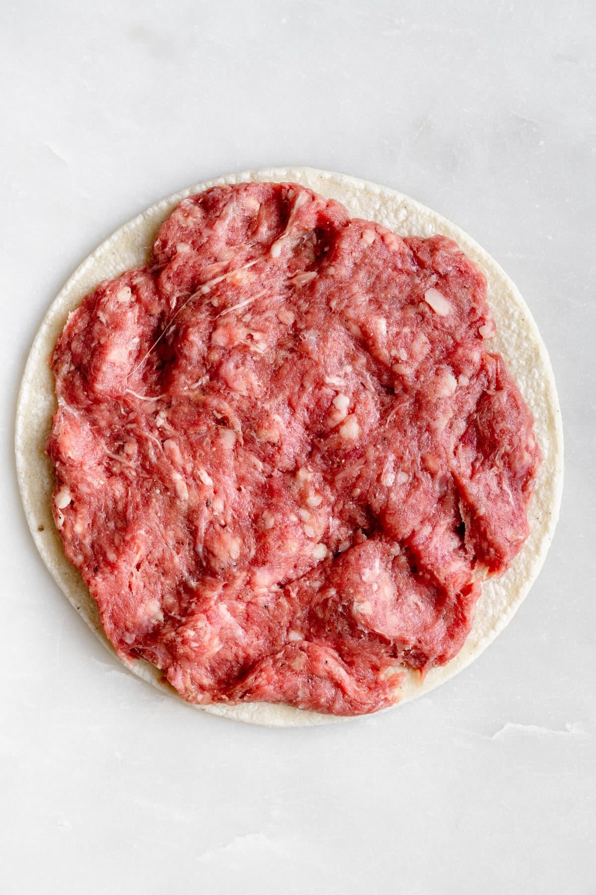 ground beef pressed into the tortilla