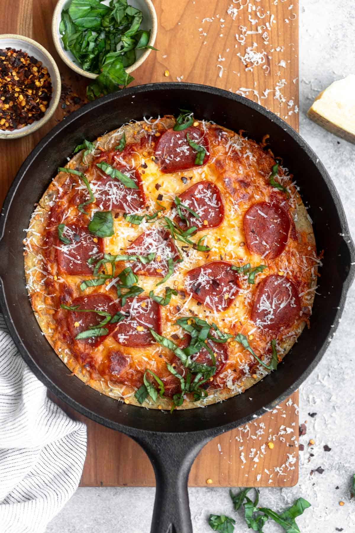 chickpea pizza crust in a cast iron skillet with sauce and cheese on top