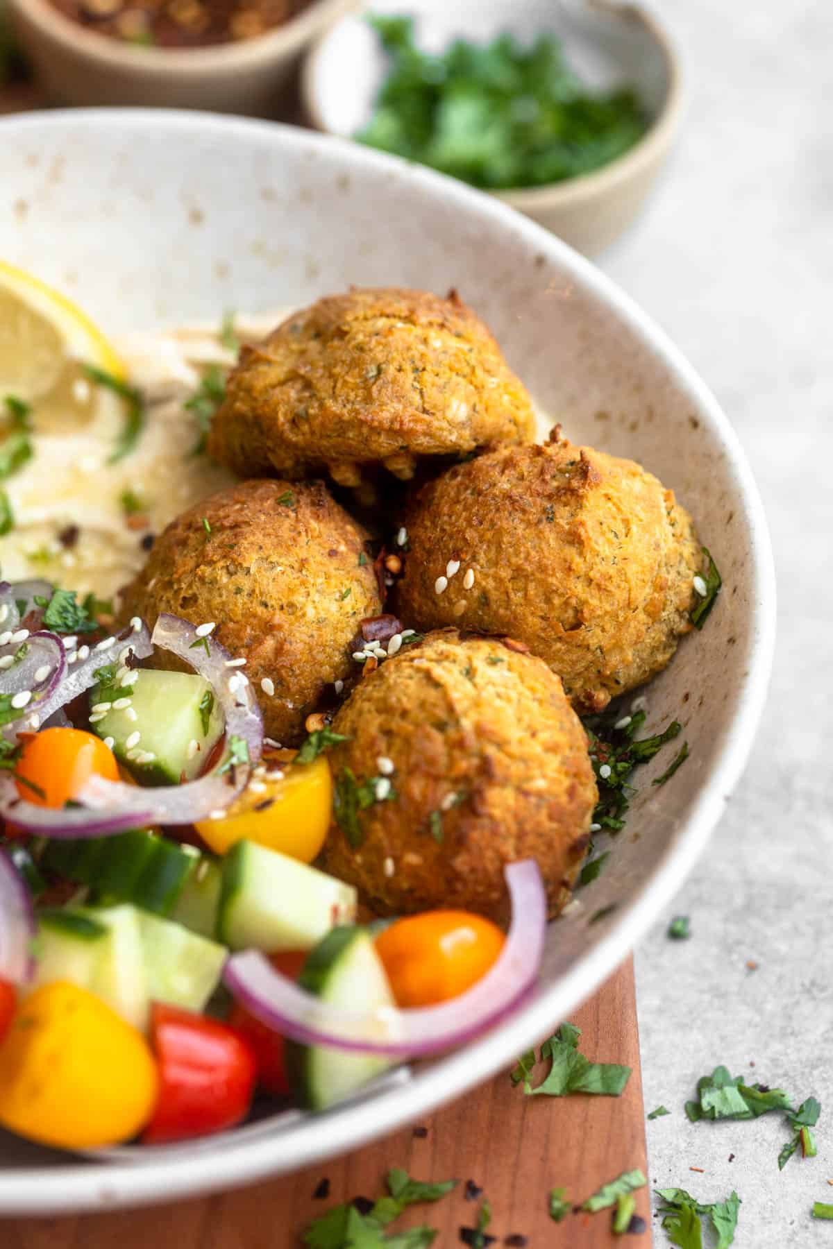air fryer falafel in a bowl with veggies and herbs