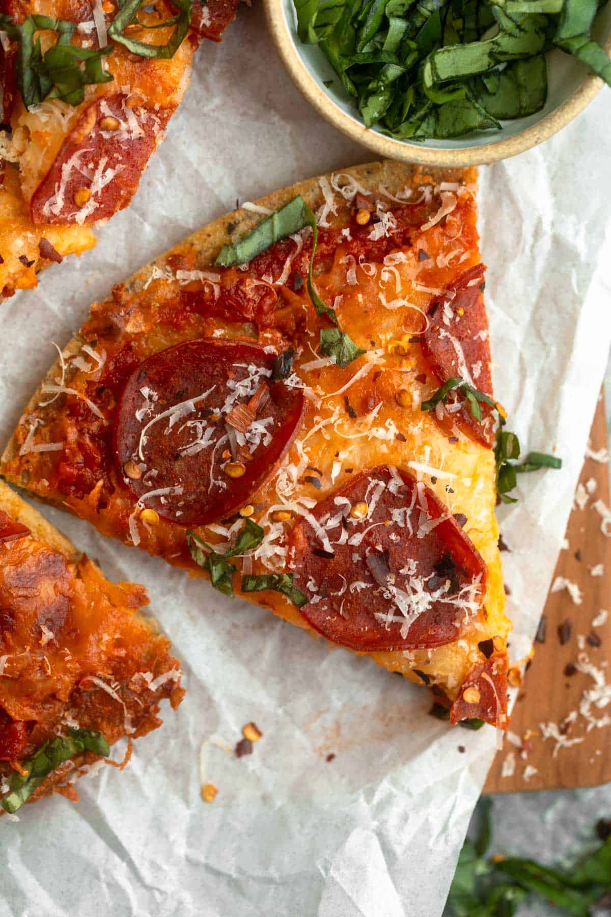 chickpea pizza crust sliced on a wood board with pepperoni
