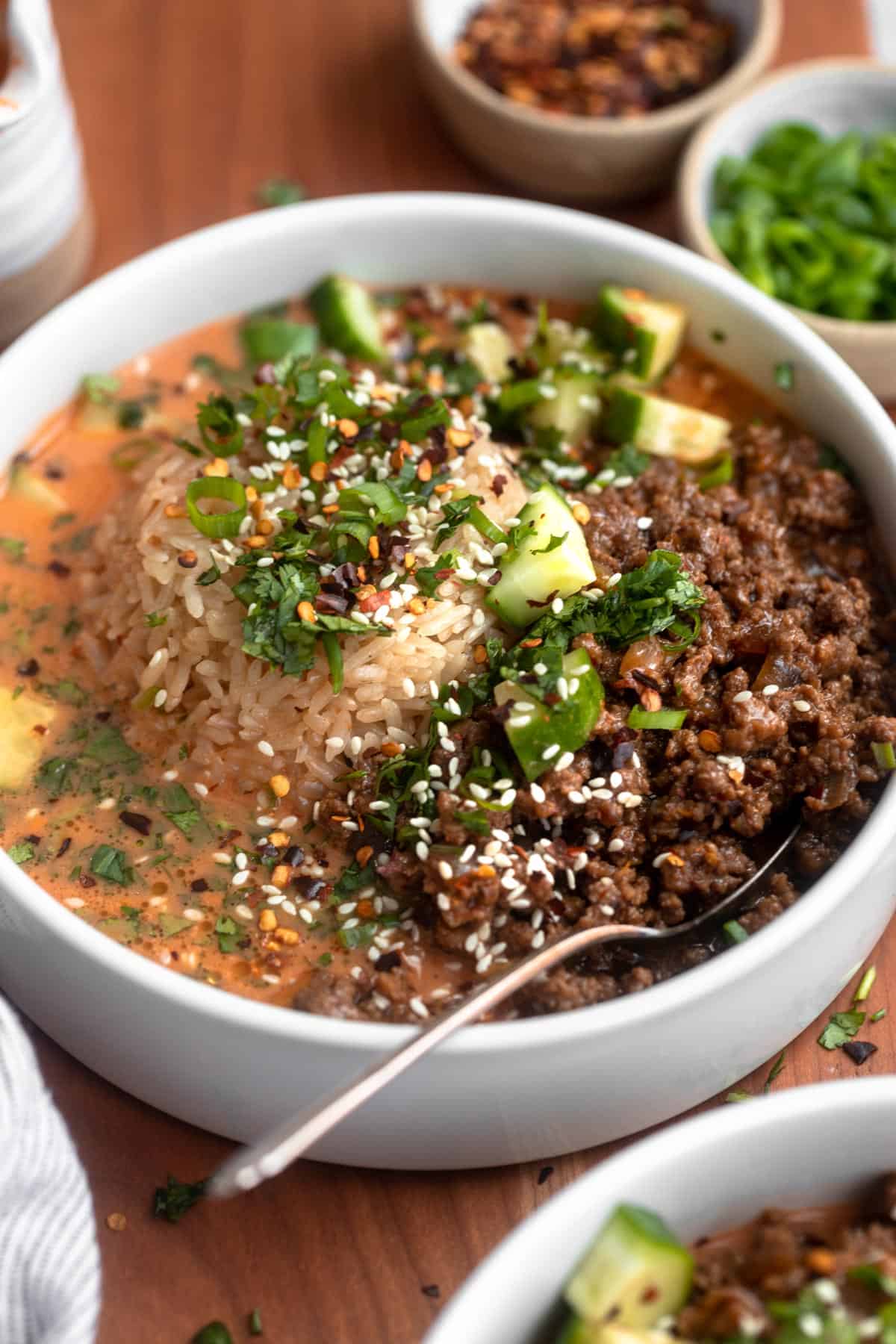 sesame beef broth bowls with cucumber and herbs on top
