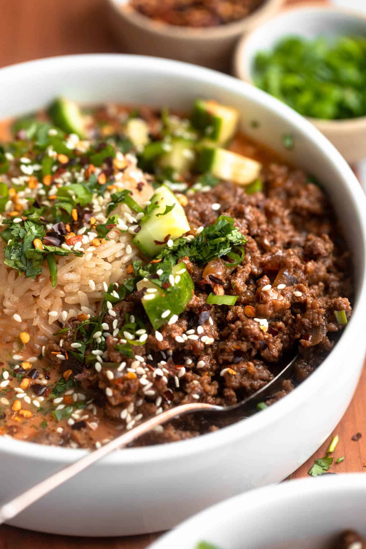 angled view of the sesame beef broth bowls with a spoon on the side