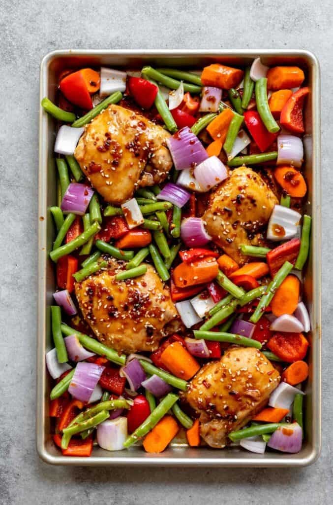 chicken and veggies on the sheet pan before cooking