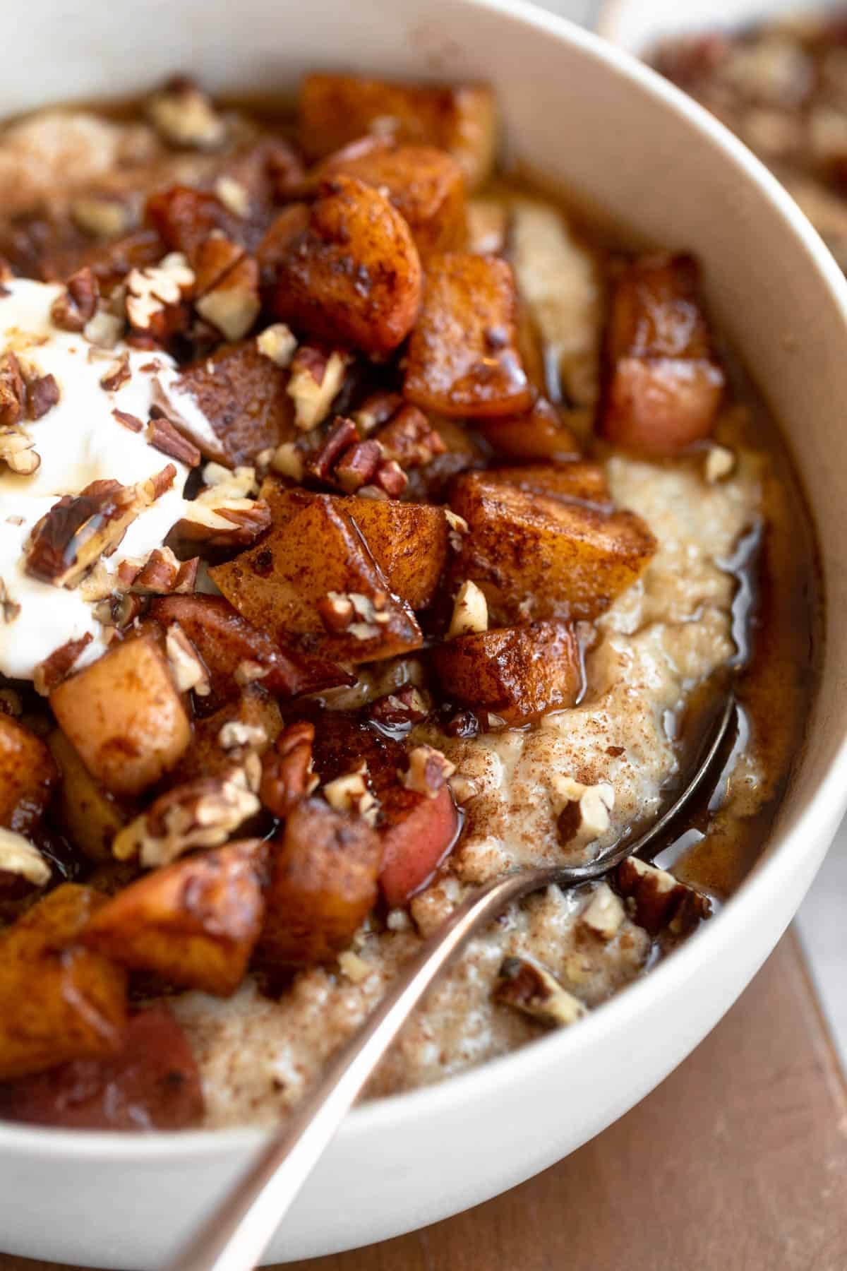 angled view of the gluten free oatmeal in a bowl with cinnamon apple on top