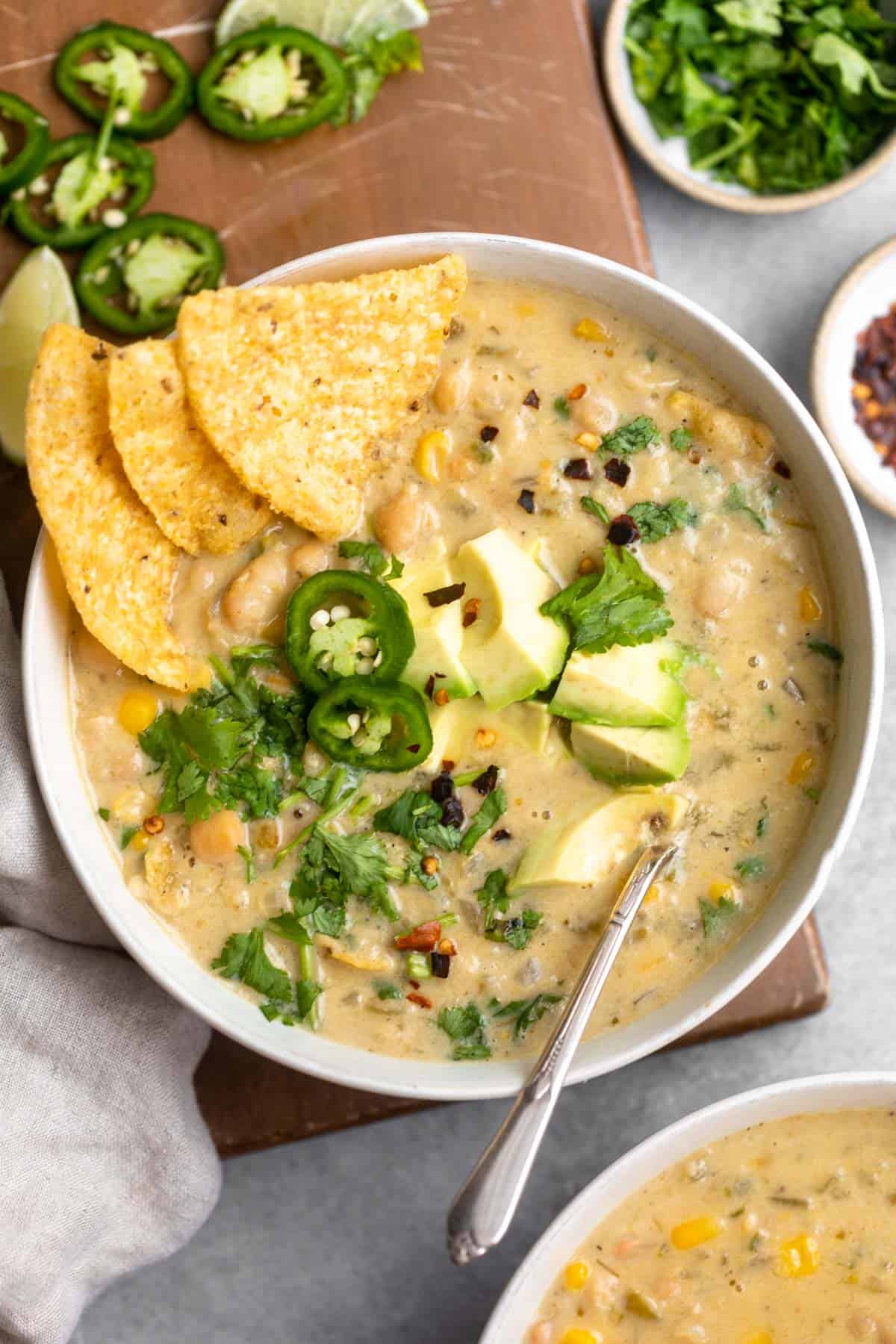 vegan white bean chili in a bowl with avocado and cilantro on top